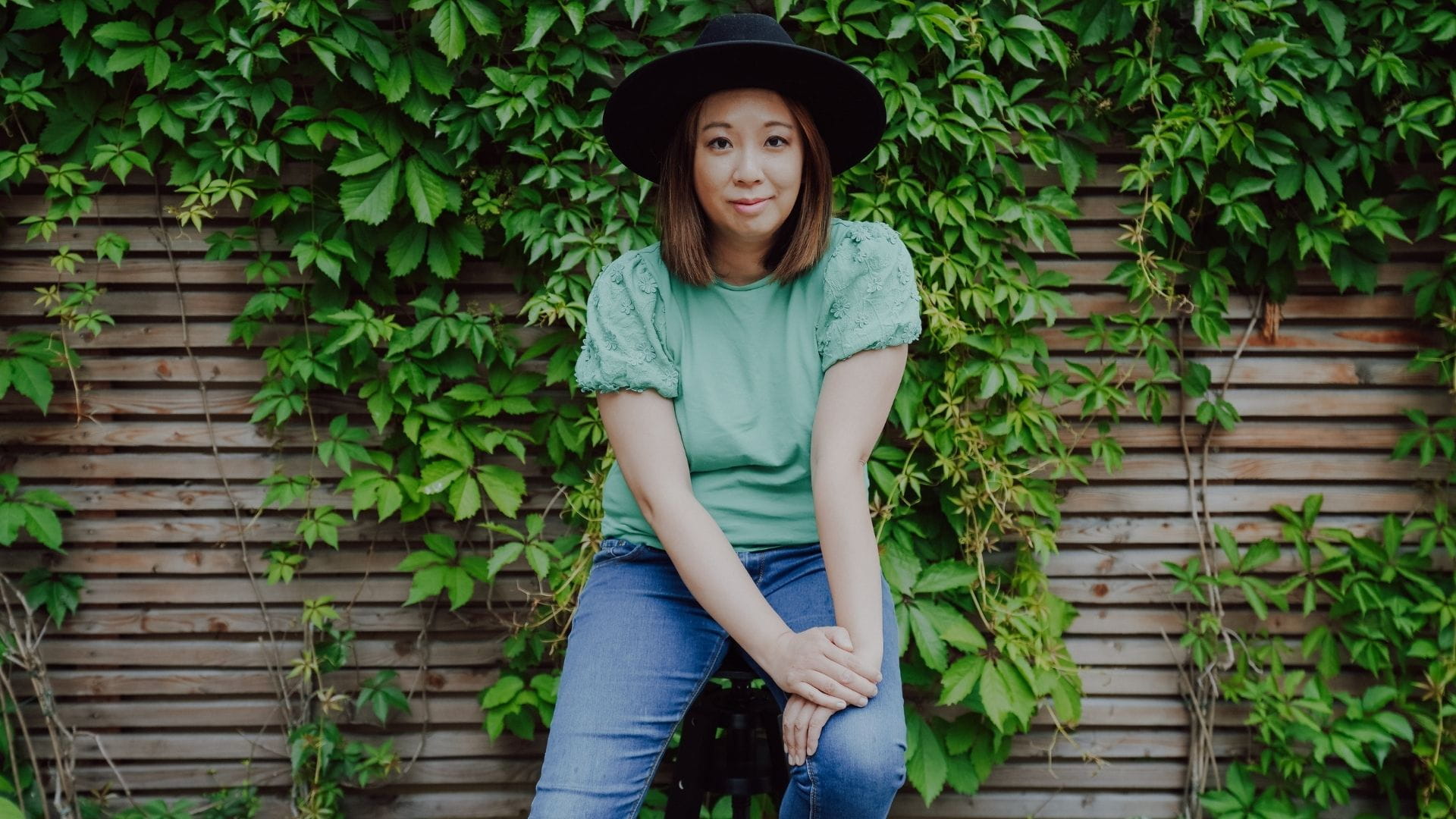 Miu Yuen-Dumke, zertifizierte TCM-Ernährungsberaterin, Portrait vor einer grünen Efeuwand
